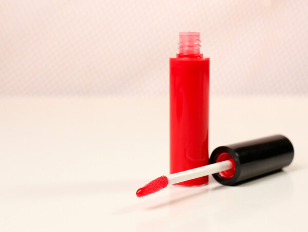 Красивый блеск для губ на розовом фоне, крупным планом
