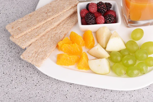 Rebanadas de frutas y bayas con pan crujiente en el plato en la mesa de cerca —  Fotos de Stock