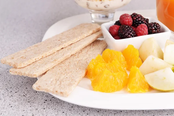 Rebanadas de frutas y bayas con pan crujiente en el plato en la mesa de cerca —  Fotos de Stock