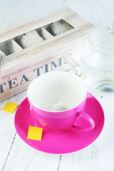 Чашка і чайник з чайними пакетами на дерев'яному столі крупним планом — стокове фото