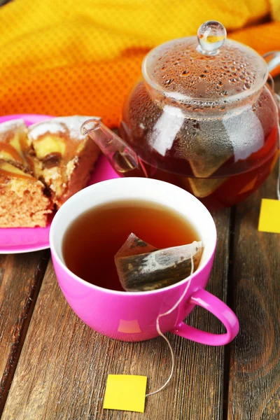 Taza con té, tetera y bolsitas de té en primer plano de mesa de madera — Foto de Stock