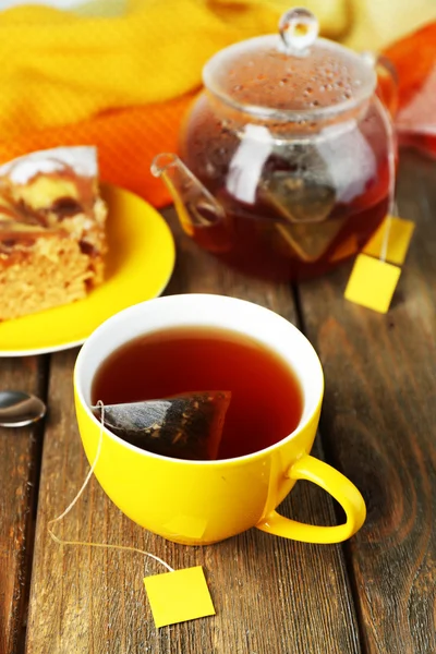 Tasse avec thé, théière et sachets de thé sur table en bois close-up — Photo