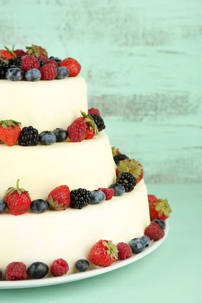 Beautiful wedding cake with berries on color wooden background — Stock Photo, Image