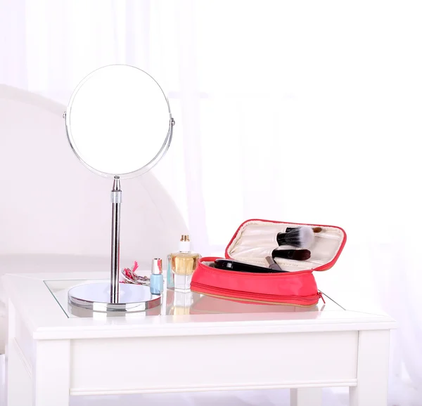 Cosmetic bag and mirror on table on light background — Stock Photo, Image