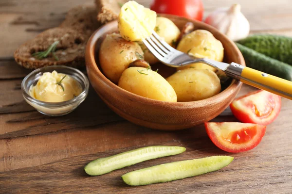 Mladí vařené brambory v míse na dřevěný stůl, zblízka — Stock fotografie