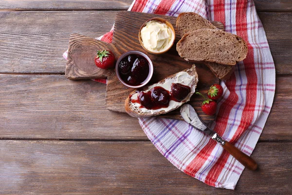 Tostadas frescas con mantequilla casera y mermelada de fresa sobre fondo de madera — Foto de Stock