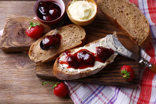 Čerstvé toasty s domácí máslem a jahodovým džemem, na dřevěné pozadí — Stock fotografie