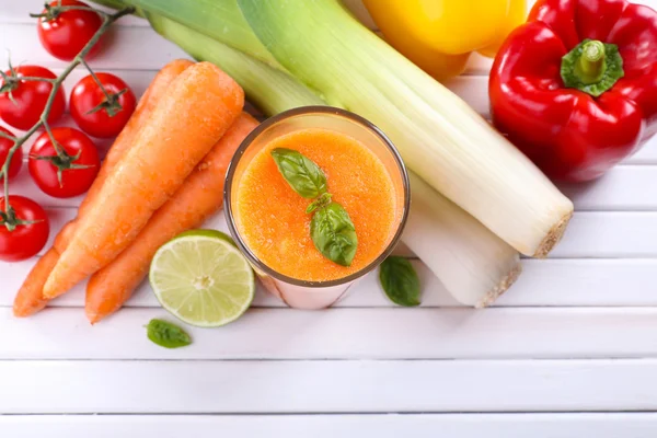 Стакан свежего морковного сока и овощей на деревянном фоне — стоковое фото