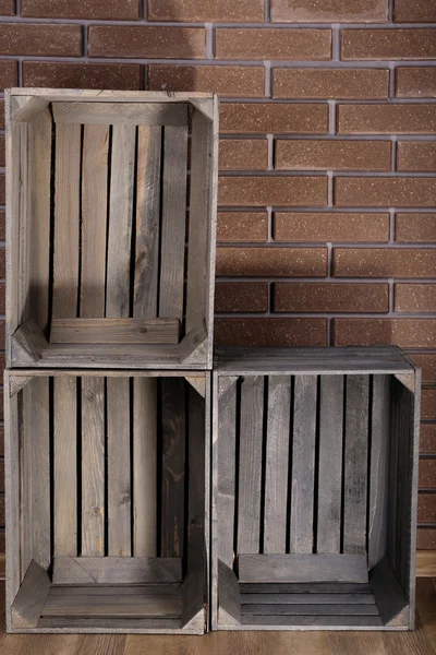 Boîtes rectangulaires en bois sur le sol devant le mur de briques — Photo