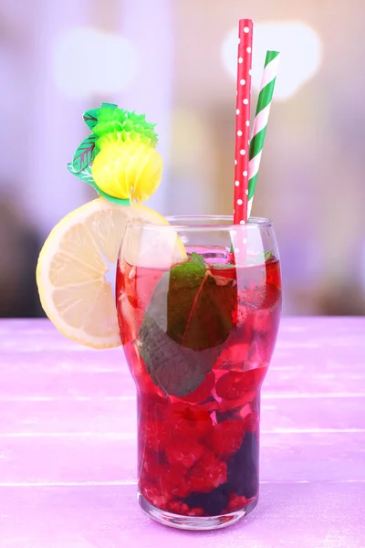 Glass of cold berry cocktail with lemon on wooden table — Stock Photo, Image