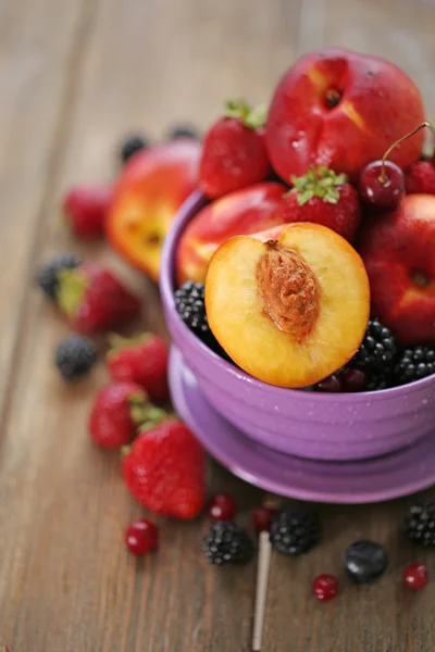 Peaches and berries in bowl on table close-up — Stock Photo, Image