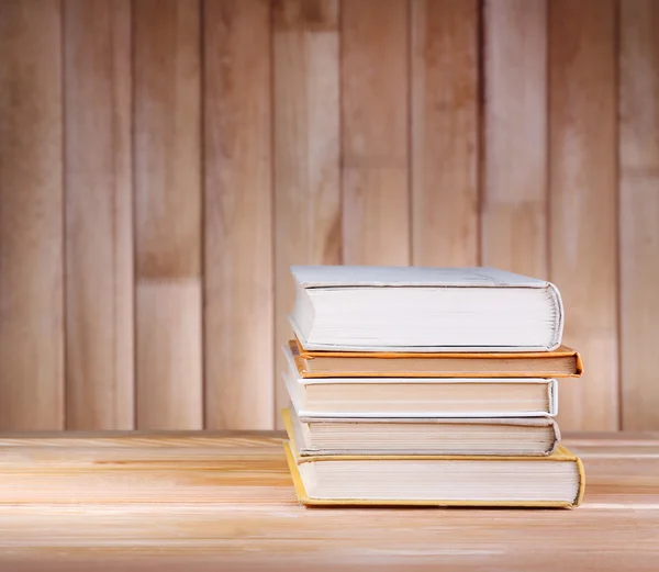Knihy na dřevěný stůl na dřevěné stěně obrazce pozadí — Stock fotografie