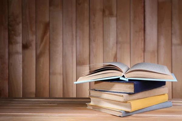 Libros sobre mesa de madera sobre fondo de pared de madera — Foto de Stock