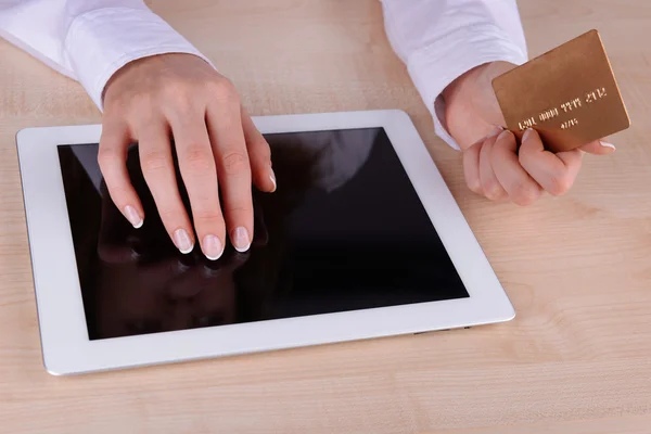 Frauenhände halten Kreditkarte und Computer-Tablet aus nächster Nähe auf dem Tisch — Stockfoto