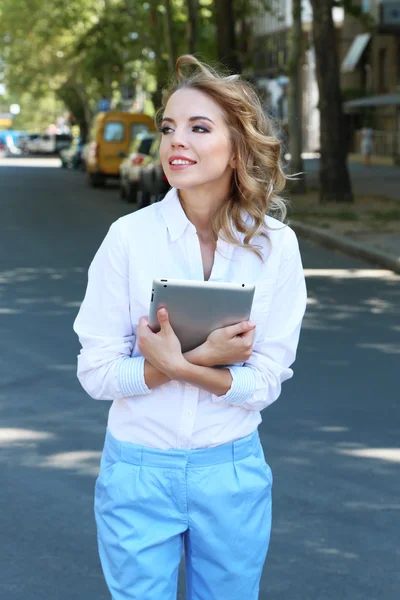 Beautiful young girl with tablet on city street — Stock Photo, Image