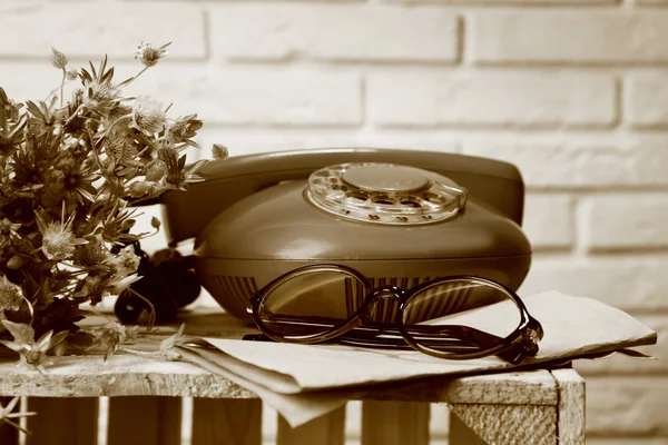 Retro telefon a sklenice na stole v odstínech šedé — Stock fotografie