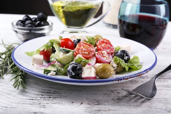 Tallrik med grekisk sallad serveras med vin och olivolja olja på träbord på mörk bakgrund — Stockfoto