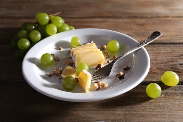 Smakelijke druif en kaas op plaat, op houten tafel — Stockfoto