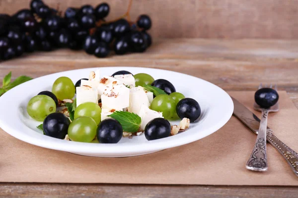 Tasty salad with grape and cheese on wooden table — Stock Photo, Image