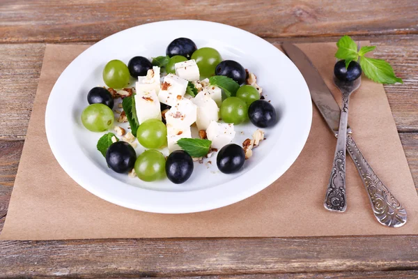 Salada saborosa com uva e queijo na mesa de madeira — Fotografia de Stock