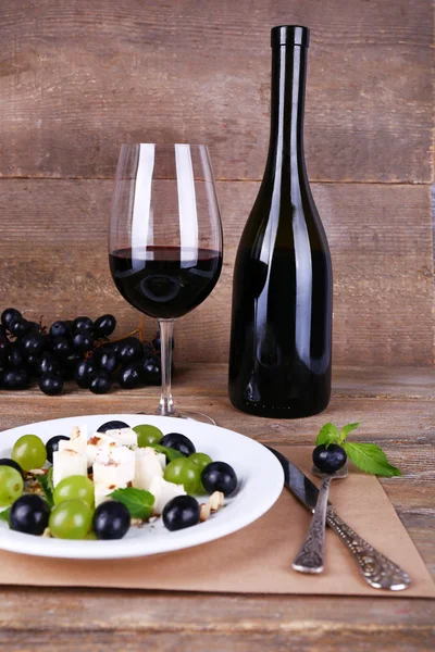 Hermosa naturaleza muerta con vino y ensalada sobre fondo de madera —  Fotos de Stock