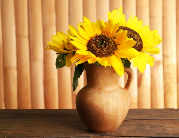 Hermoso ramo de girasoles en jarra sobre mesa sobre fondo de madera — Foto de Stock