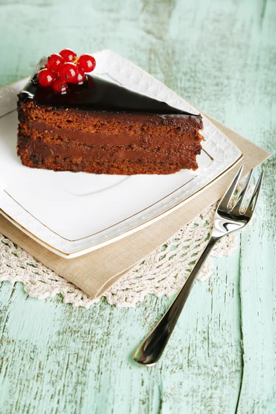 Chocolate cake with fresh berries on plate, on color wooden background — Stock Photo, Image