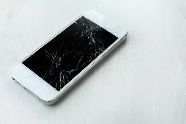 Moderne mobiele telefoon met gebroken scherm op houten achtergrond — Stockfoto