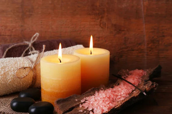 Piedras de spa con velas y sal marina sobre fondo de madera — Foto de Stock