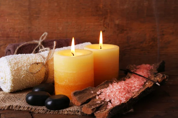 Piedras de spa con velas y sal marina sobre fondo de madera — Foto de Stock