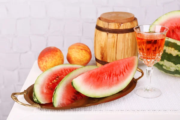 Composition de pastèque mûre, fruits, vin rose en verre et tonneau en bois sur table en bois de couleur, sur fond clair — Photo