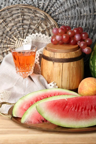 Skład dojrzały arbuz, owoce, wino różowe w szklane i drewniane beczki na drewnianej tablicy kolorów, na tle cegły — Zdjęcie stockowe