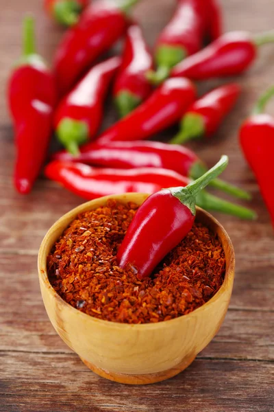 Milled red chili pepper in bowl on wooden background — Stock Photo, Image