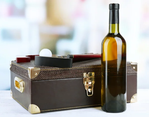 Juego de golf en maleta con botella de vino sobre mesa sobre fondo brillante — Foto de Stock