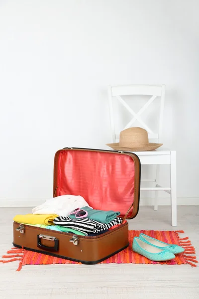 Female clothes in old suitcase on light background — Stock Photo, Image