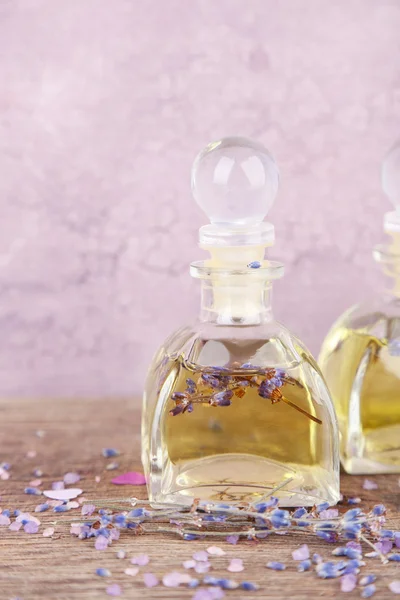 Spa still life with lavender oil and flowers on wooden table, on pink background — Stock Photo, Image