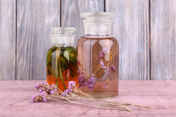 Flaschen Kräutertinktur und Brunch mit Blumen auf einem Holztisch vor einer Holzwand — Stockfoto