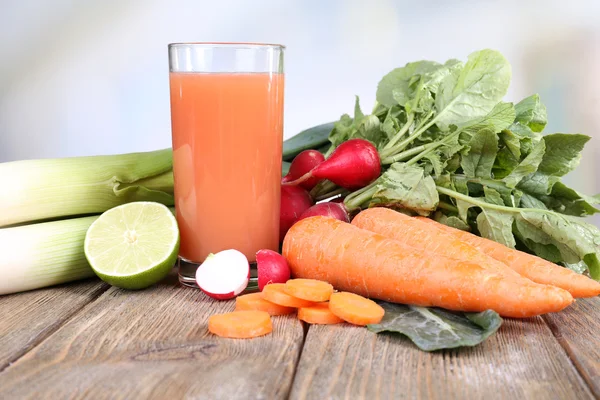 Färsk morotsjuice med grönsaker på träbord — Stockfoto