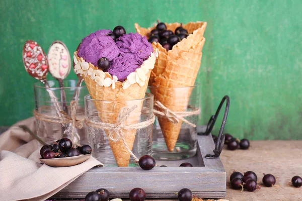 Gustoso gelato con bacche in coni di cialde su sfondo verde in legno — Foto Stock