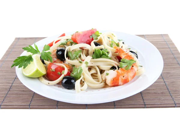 Fresh prawns with spaghetti, olives, tomatoes and parsley in a big round plate on a napkin on white background isolated — Stock Photo, Image