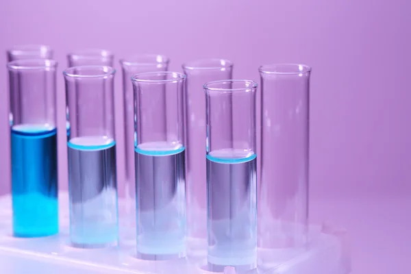 Test-tubes with blue liquid on purple background — Stock Photo, Image