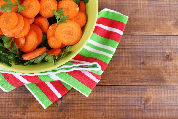 Trozos de zanahoria, acedera y perejil en un tazón redondo verde sobre una servilleta sobre fondo de madera —  Fotos de Stock