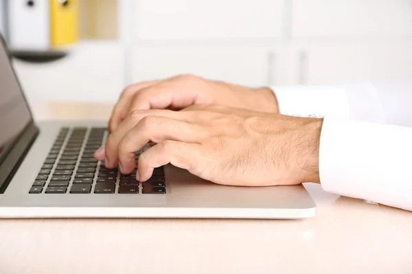 Man som arbetar på laptop på träbord på mappbakgrund — Stockfoto