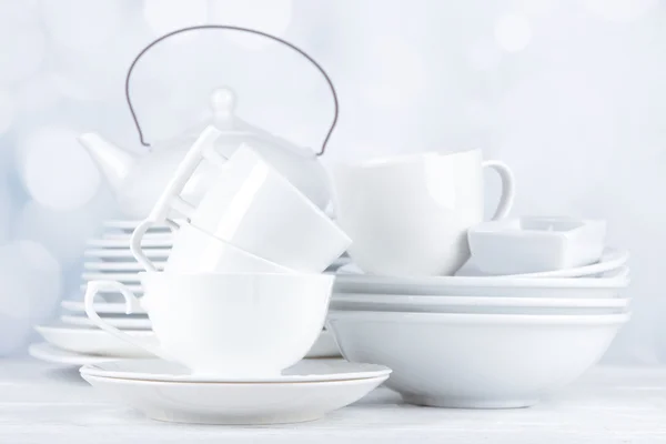 Açık renkli ahşap masaya üzerinde beyaz çanak çömlek ve mutfak gereçleri — Stok fotoğraf