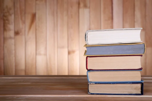 Libri su tavolo in legno su fondo parete in legno — Foto Stock