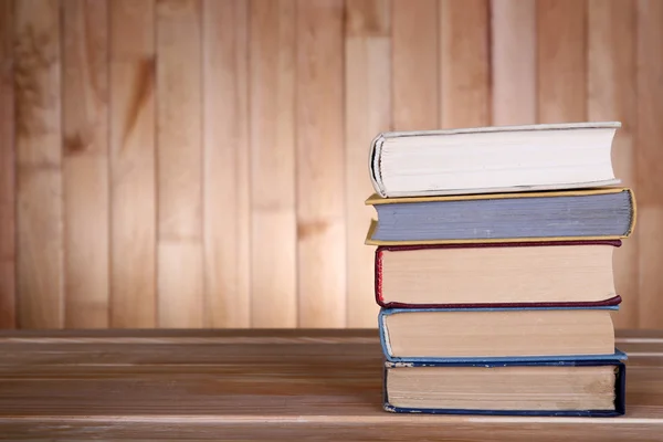 Books on wooden table on wooden wall background — Stock Photo, Image