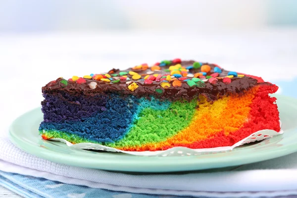 Delicious rainbow cake on plate, on table, on light background — Stock Photo, Image