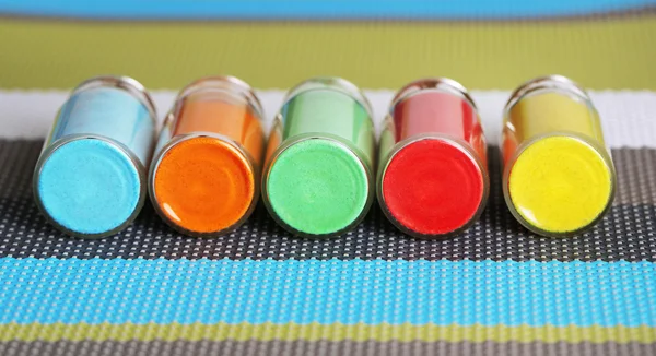 Bottles with colorful dry pigments on bright background — Stock Photo, Image