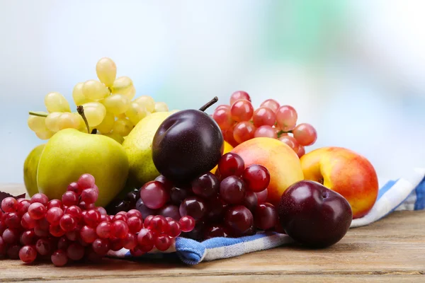 Assortiment van sappige vruchten op servet, op tafel, op lichte achtergrond — Stockfoto