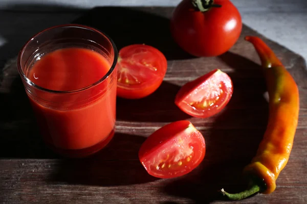 Szklankę soku pomidorowego z przypraw i świeżych pomidorów na drewnianym stole. z ciemnym tle — Zdjęcie stockowe